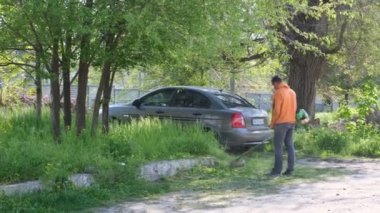 Bahçıvan çimleri biçiyor, çim biçme makinesi bölgeyi temizliyor. Bahçe budayıcı. Bahçedeki yüksek otları biçiyor.