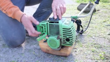 Bahçıvan çimleri biçiyor, çim biçme makinesi bölgeyi temizliyor. Bahçe budayıcı. Bahçedeki yüksek otları biçiyor.