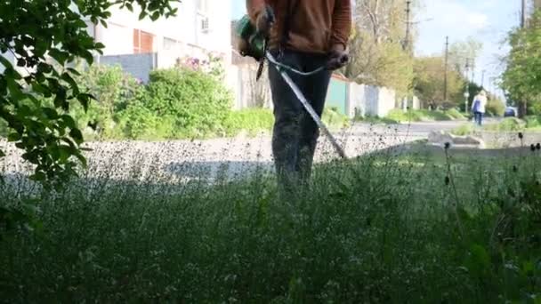 芝生を刈る庭師の男 エリアをきれいにするための手動芝生の芝刈り機 ガーデントリマー 庭で高い雑草を刈る — ストック動画