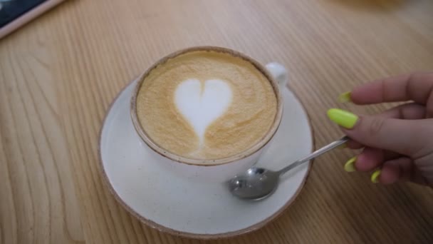 一杯卡布奇诺咖啡在咖啡店的桌子上咖啡牛奶在公共场所饮用 奶泡心 — 图库视频影像