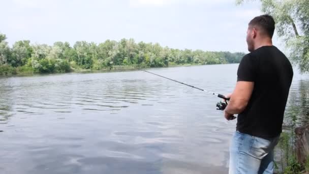浮き回転する釣竿の上の岸から釣り男 パイクのためのルアー 水の近くの森の中で孤独 — ストック動画