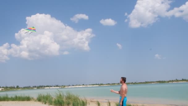Ένας Λεπτός Άντρας Στην Παραλία Πετάει Έναν Πολύχρωμο Χαρταετό Ενεργή — Αρχείο Βίντεο