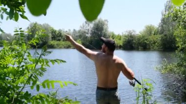 Bir adam nehir kıyısında balık tutuyor. Aktif balıkçılık. Yavaş çekim.