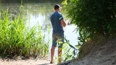 Bir adam nehir kıyısında balık tutuyor. Aktif balıkçılık. Yavaş çekim.