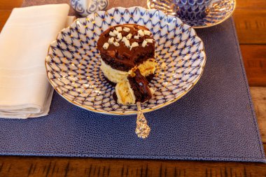 Süslü bir Çin tabağında altın ve gümüş kaşıkla kaplanmış koyu ve beyaz çikolata tatlısı..