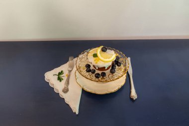 Lezzetli kremalı limonlu ekmek ve altın işlemeli antika bir komposto üzerine yaban mersini..