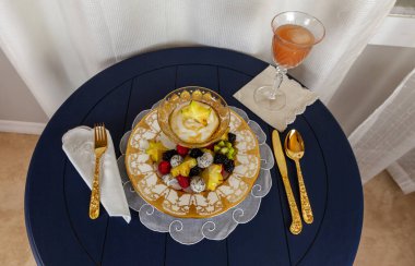 Fancy fruit salad with dragon fruit, star fruit, raspberries, blackberries, and kiwi on a gold encrusted plate with Greek yogurt. clipart