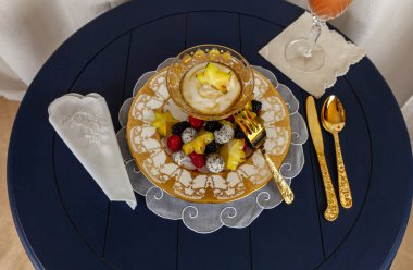 Fancy fruit salad with dragon fruit, star fruit, raspberries, blackberries, and kiwi on a gold encrusted plate with Greek yogurt. clipart