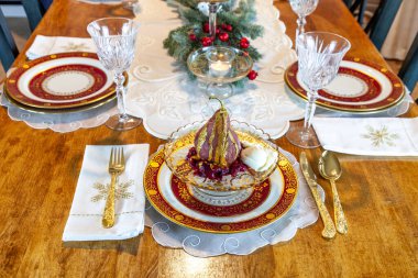 Şarap ve baharatla kaynatılmış bir armut tatlısı Noel 'de bir tatil masasındaki altın bir tabakta ev yapımı kızılcık sosunun üzerinde duruyor..