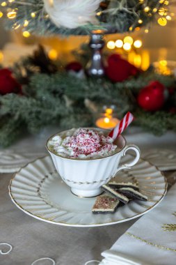 Naneli sıcak çikolata, çırpılmış krema ve noel ışıkları olan bir masada naneli şeker kabuğu..