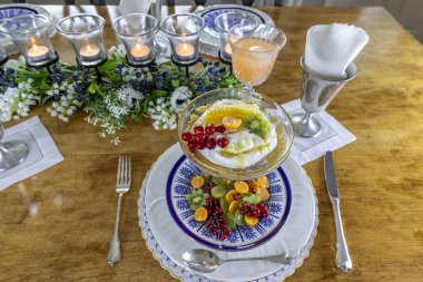 Meyve ve Yunan yoğurdu kahvaltısı, bir dilim bal tarağı ve altın böğürtlen resmi bir masada..