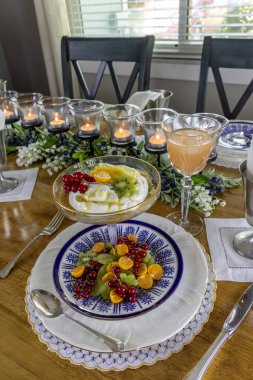 Meyve ve Yunan yoğurdu kahvaltısı, bir dilim bal tarağı ve altın böğürtlen resmi bir masada..