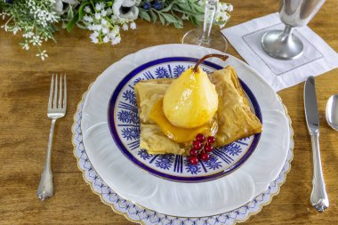 Armut şampanyada haşlanır, zencefil ve tutkulu meyve suyu ve porselen üzerinde puf böreği..