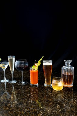 Large group of cocktails including a margarita, martini, champagne, wine, beer, bloody Mary and scotch on a black background. clipart