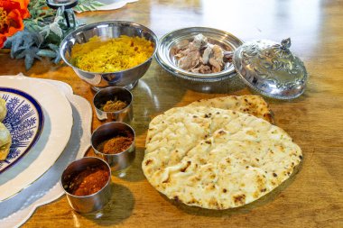 Çeşitli baharatlı Samosalar, safran pirinci, naan ekmeği ve ördek eti güzel porselen tabaklar üzerinde Hint yemeği..