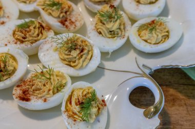 Paskalya süslemeleri, zambaklar, kelebekler, kristaller ve mumlarla süslenmiş, porselen bir tabakta içi altın dolu yumurtalar..