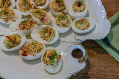 Paskalya süslemeleri, zambaklar, kelebekler, kristaller ve mumlarla süslenmiş, porselen bir tabakta içi altın dolu yumurtalar..