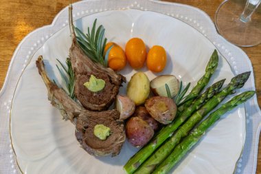 Biberiyeli kuzu rostosu ve patates ve kuşkonmazla süslenmiş Paskalya süslemeleri.