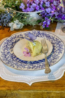 Eflatun ve limonlu kek, şekerli gofret kelebekleri ve mor masa düzeninde garnitür için çiçek..