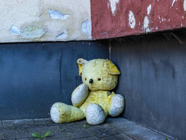 Şehirde duvarın yanında bir oyuncak ayı oturuyor.