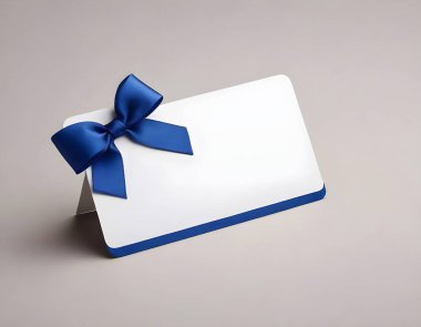 A white gift card adorned with a satin blue ribbon is centered on a neutral, light grey backdrop. The card provides ample space for a personalized message and is perfect for special occasions. clipart