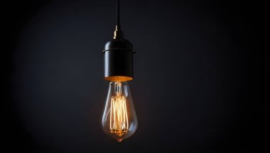Tek bir Edison ampulü siyah bir kabloya asılı. Ampul parlak bir şekilde parlıyor, çevreye sıcak bir ışık saçıyor..