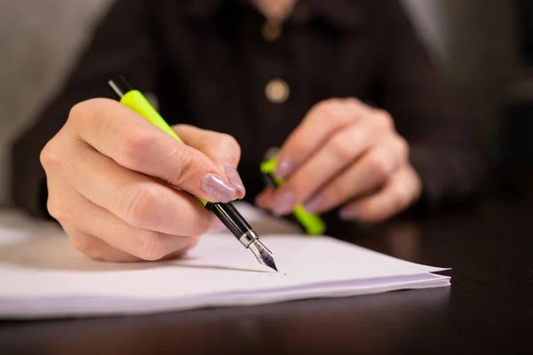Businesswoman writes with a calligraphy pen on blank paper