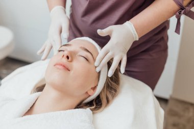 Kadın güzellik kliniğinde yüz ve vücut bakımı görüyor.