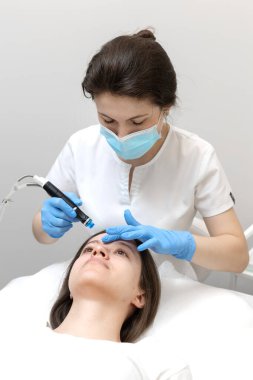 Akıllı kozmetolog, hidrakiyal prosedür sırasında modern bir cihaz kullanıyor.