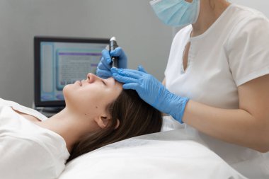 Akıllı kozmetolog, hidrakiyal prosedür sırasında modern bir cihaz kullanıyor.