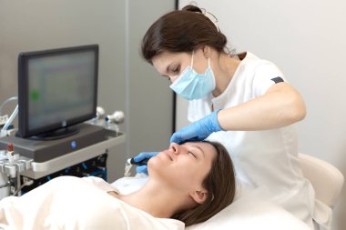 Akıllı kozmetolog, hidrakiyal prosedür sırasında modern bir cihaz kullanıyor.