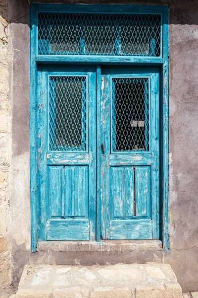 Eski yıpranmış ve benzin ile boyanmış çift katlı ahşap kapılı bir eve giriş..