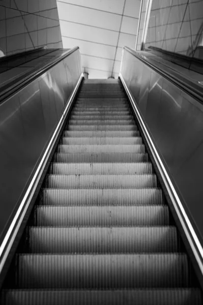 stock image The view from a deep position over a modern stainless steel escalator without people in monochrome.