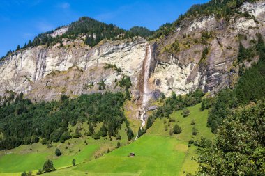 Avusturya Alplerinde yüksek bir kayalık dağın üzerinde yüksek bir şelale çağlıyor..