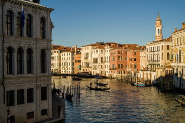 Venetian canal scene: colorful buildings, gondolas, and clear sky. clipart