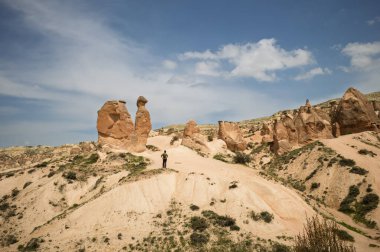 Bir yürüyüşçü Kapadokya 'nın gerçeküstü manzarasına hayran. Rüzgar ve su yüzyıllar boyunca bu eşsiz kaya oluşumlarını şekillendirdi..