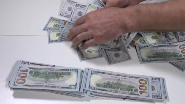 男性の手はドルを取り 白いテーブルの背景にスタックに入れます 100ドルの銀行券 — ストック動画
