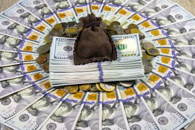 Dünyanın dört bir yanından gelen bir yığın bozuk paraya karşılık bir çuval dolusu Amerikan doları ve 100 dolarlık banknotlar bir daire şeklinde dizilmiş. Bankacılık ve finansal konsept