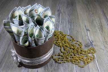 100 dolarlık banknotlarla dolu bir silindir şeklinde bir hediye kutusu gri ahşap bir masada bir tüpe konmuş. Bankacılık ve finansal konsept