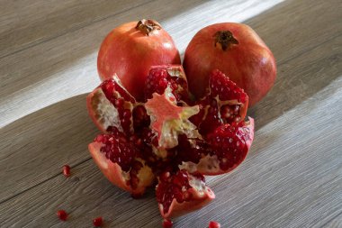 İki taze nar ve gri ahşap bir masada bir kesik. Yakın plan.