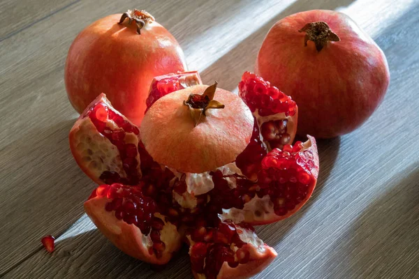 İki taze nar ve gri ahşap bir masada bir kesik. Yakın plan.