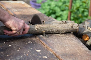 Endüstriyel elektrikli elektrikli elektrikli testere ile odun kesen bir işçinin elleri. Kış için odun topluyorum, kereste fabrikası. Daire testereli odun testeresi