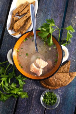 Mavi ahşap arka planda maydanozlu taze balık çorbası..