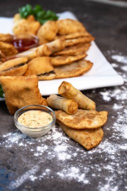 Gri arka planda çeşitli Asya hamur işleri var.