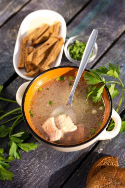 Mavi ahşap arka planda kıtır kıtır balık çorbası ve maydanoz manzarası..