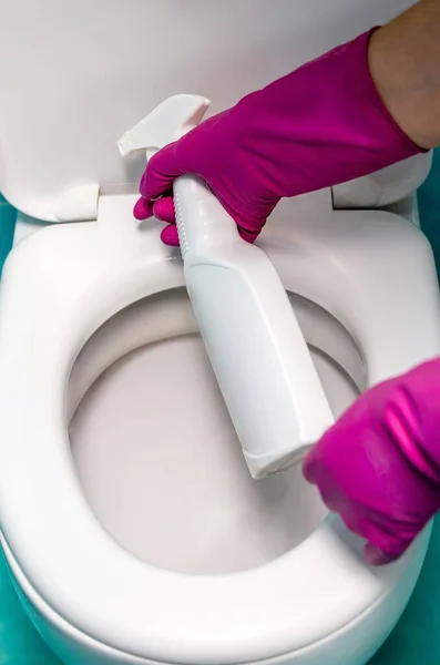 close-up of a hand spraying detergent on the toilet. toilet cleaning.