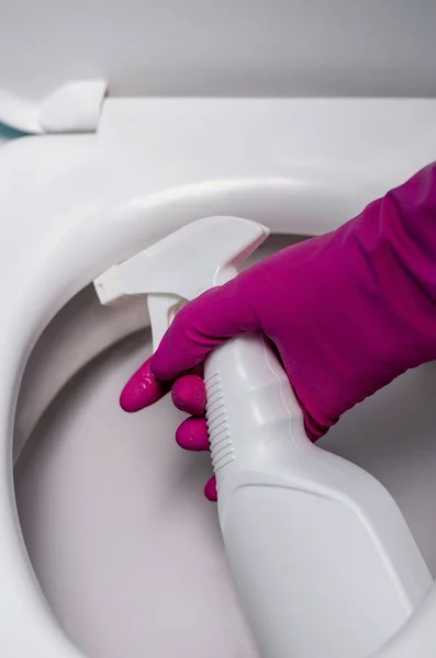 close-up of a hand spraying detergent on the toilet. toilet cleaning.