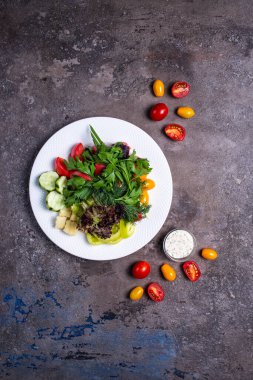 Sebze ve sebze manzarası beyaz bir tabakta koyu bir arka planda..