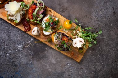 Tahta bir tahtanın üzerinde değişik aromalı çeşitli bruschetta..
