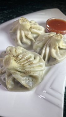 Kırmızı acı soslu, beyaz tabakta üç hinkali..